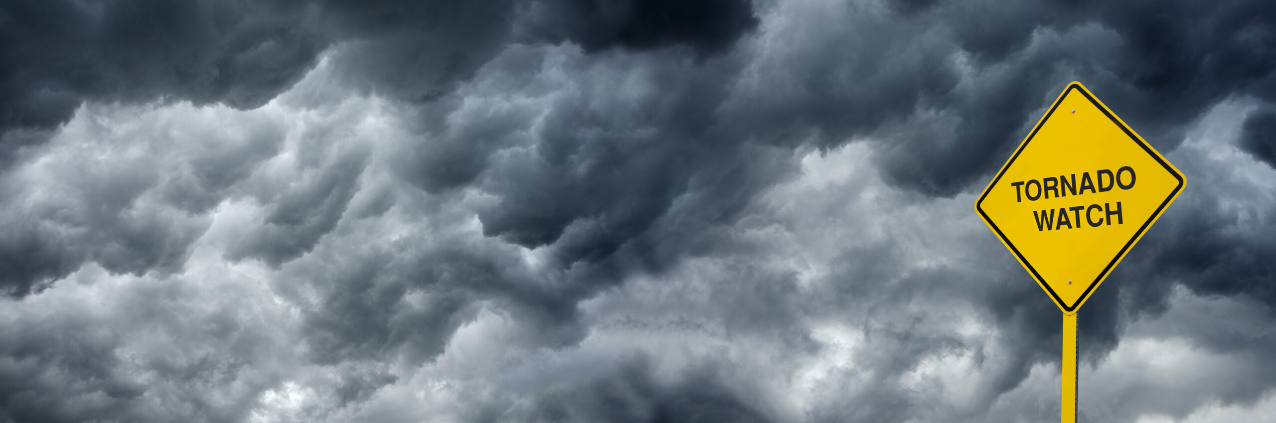 A Caution Sign in front of storm clouds warning of "Tornado Watch." Ultra wide angle/Panoramic view can also be used for web and billboard applications.